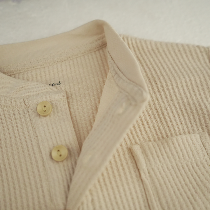 Close-up of almond peach waffle thermal baby top with button details FN-6519.